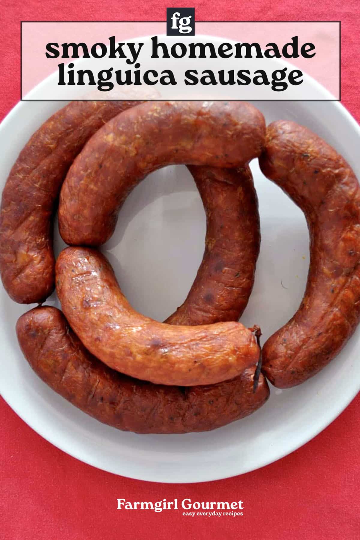 Four smoked homemade linguica sausages are arranged in a circular pattern on a white plate. The background is bright pink, with text above and below the image describing the dish.