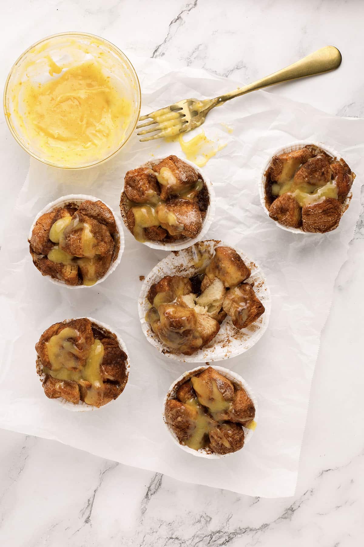 Glazed Monkey Bread Muffins with orange zest garnish on marble background.