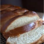 Braided honey challah sliced on board