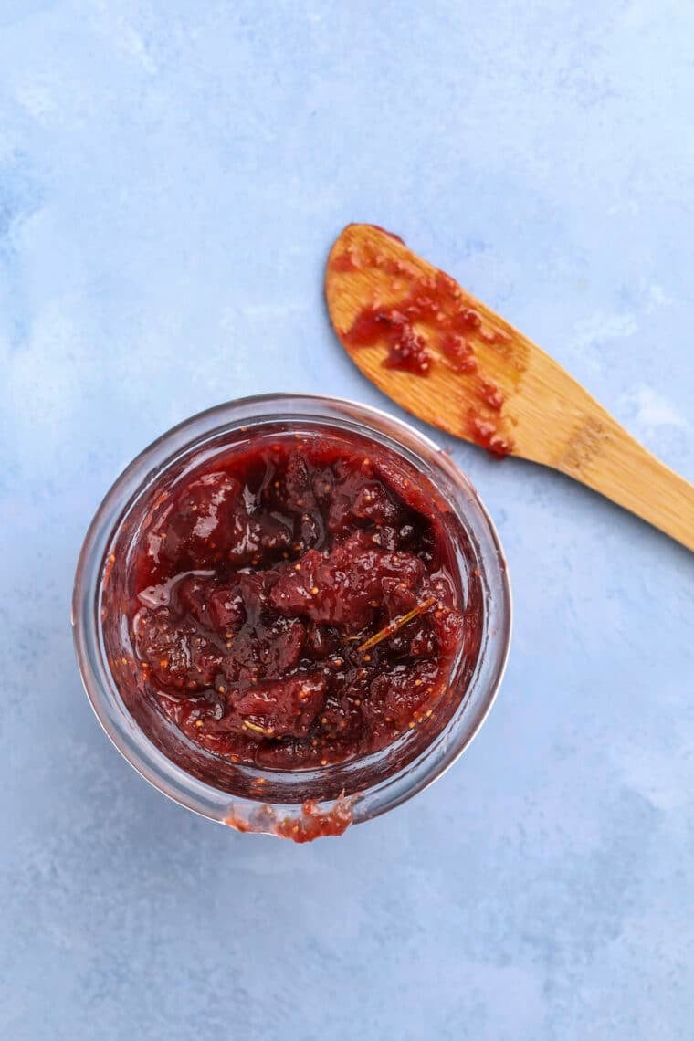 overhead shot of rosemary fig jam in a jar with a wooden knife