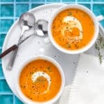 Close-up of soup garnished with fresh thyme leaves and a drizzle of cream