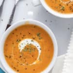 Close-up of soup garnished with fresh thyme and a drizzle of cream
