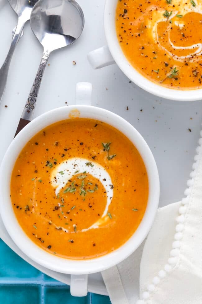 Close-up of soup garnished with fresh thyme and a drizzle of cream