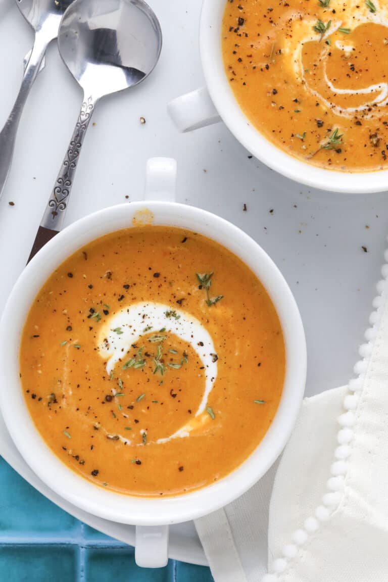 Close-up of soup garnished with fresh thyme and a drizzle of cream