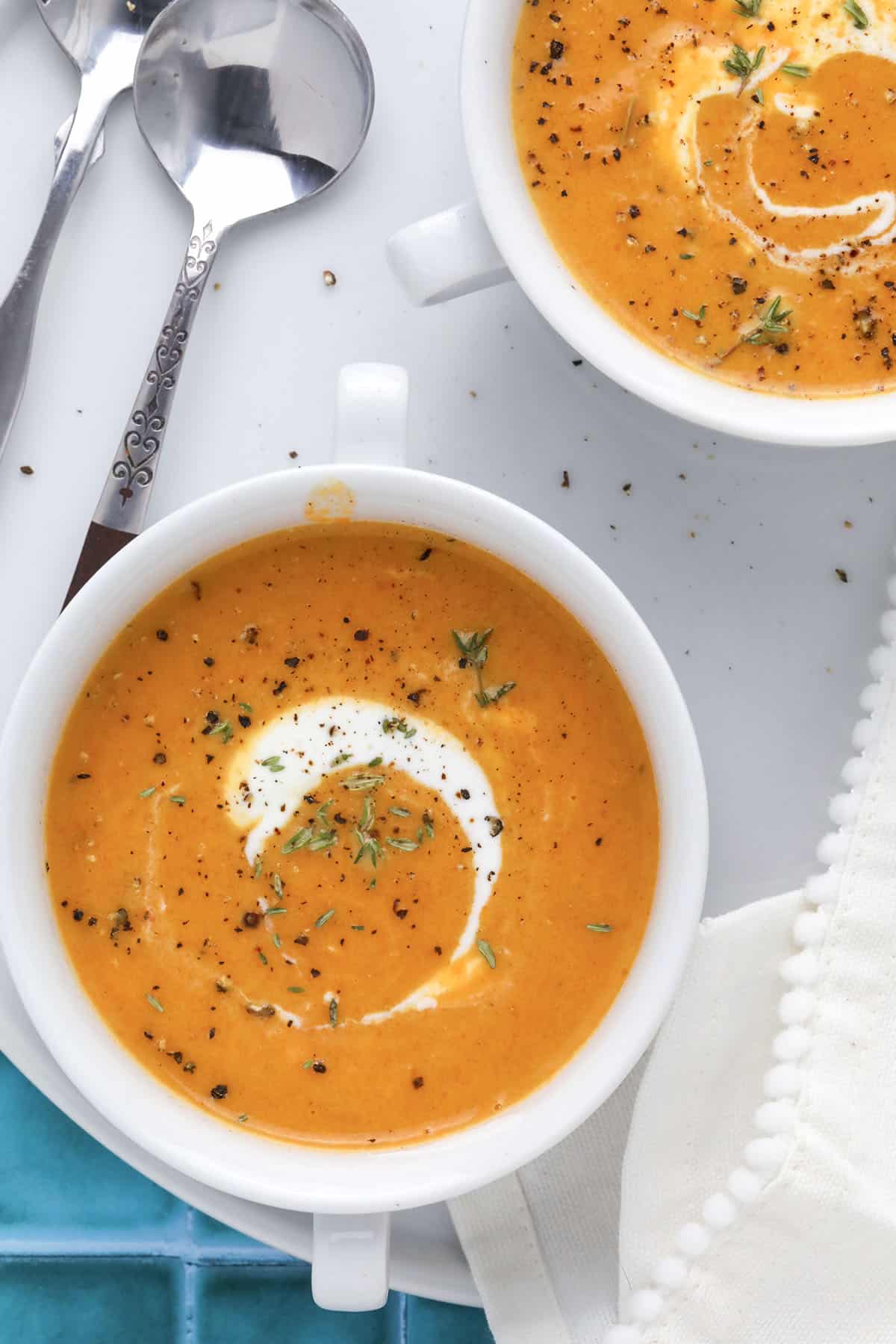 Close-up of soup garnished with fresh thyme and a drizzle of cream