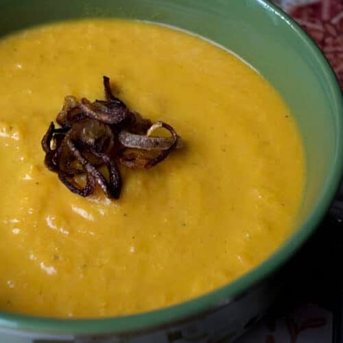 Bowl of Curried Carrot and Apple Soup with crispy fried shallots on top