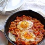 Shakshuka in cast-iron skillet with poached eggs and chile thread garnish