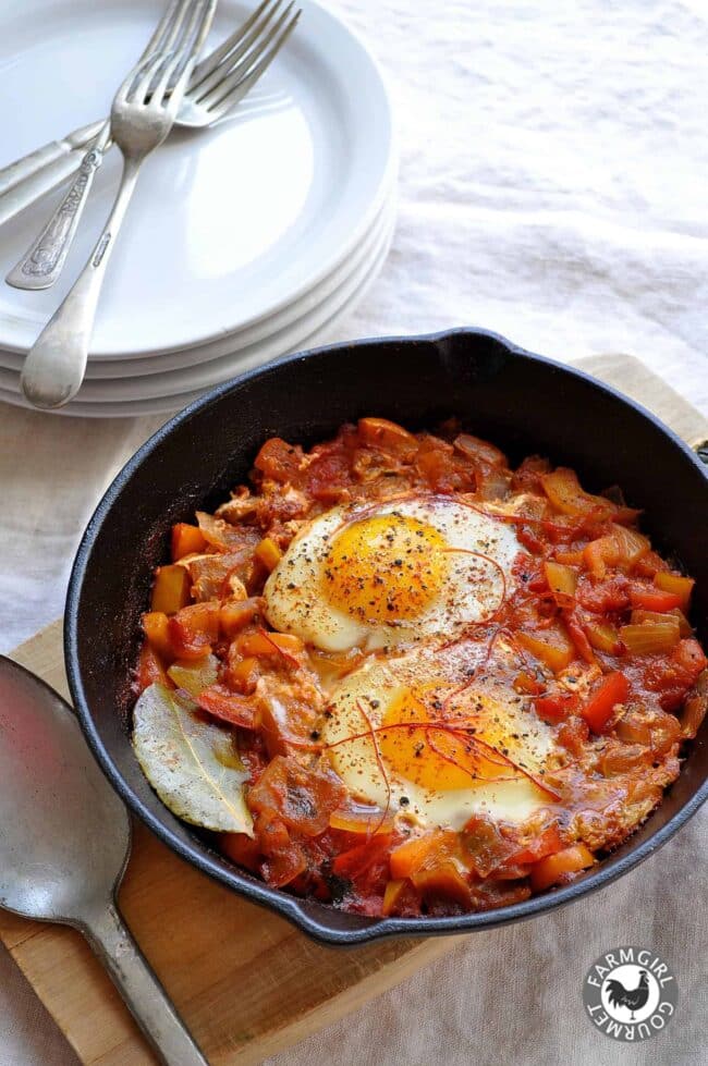 Shakshuka in cast-iron skillet with poached eggs and chile thread garnish