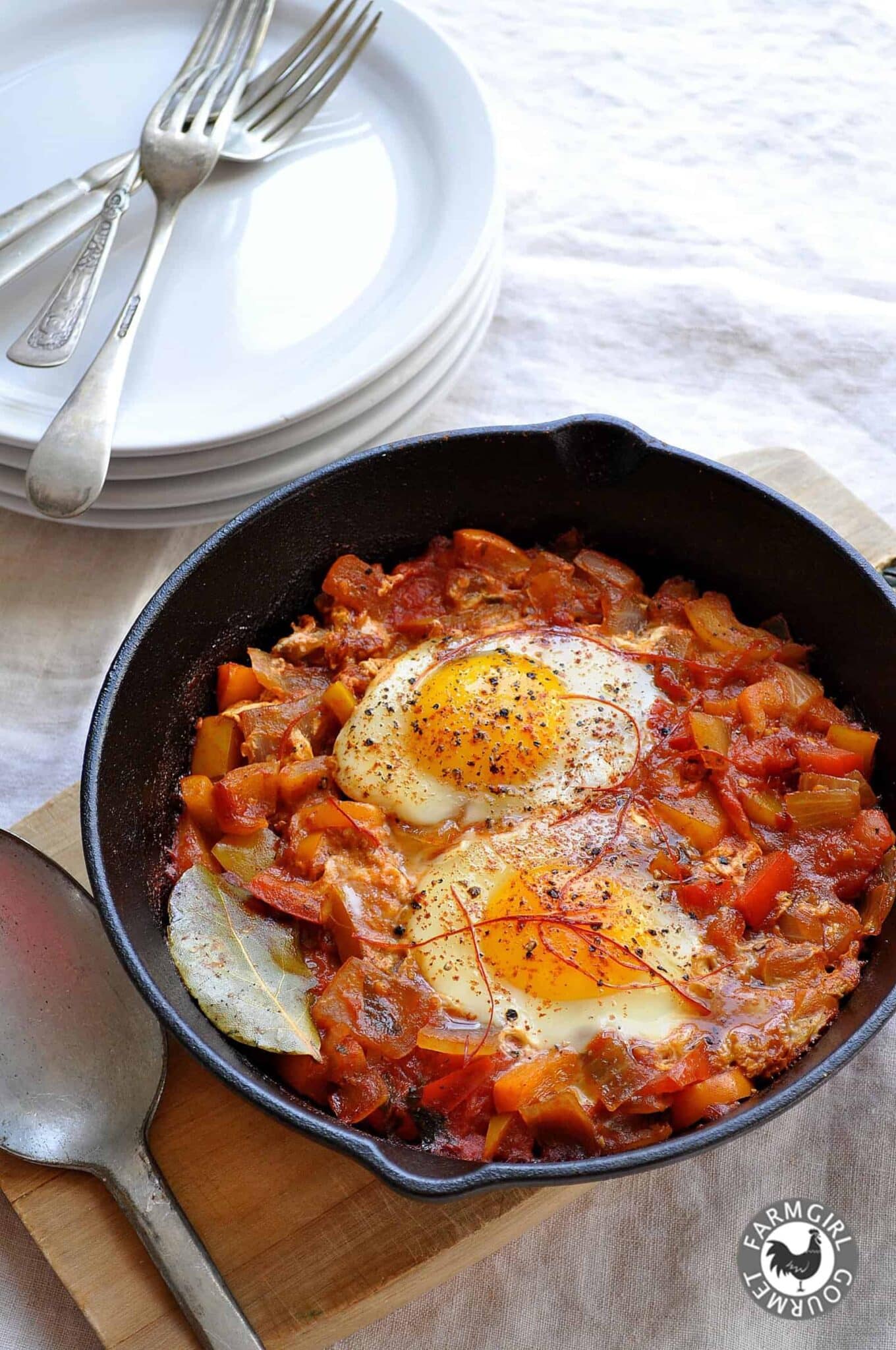Shakshuka in cast-iron skillet with poached eggs and Korean chile thread garnish