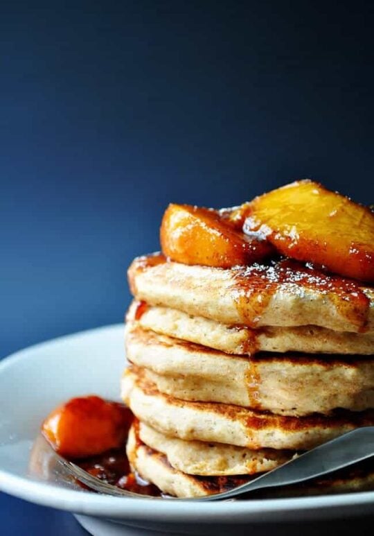 whole wheat pancakes made with applesauce and topped with fresh peaches