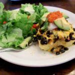 black bean polenta casserole on a plate with salad