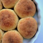 Freshly baked cheese studded dinner rolls in a pan with golden crust