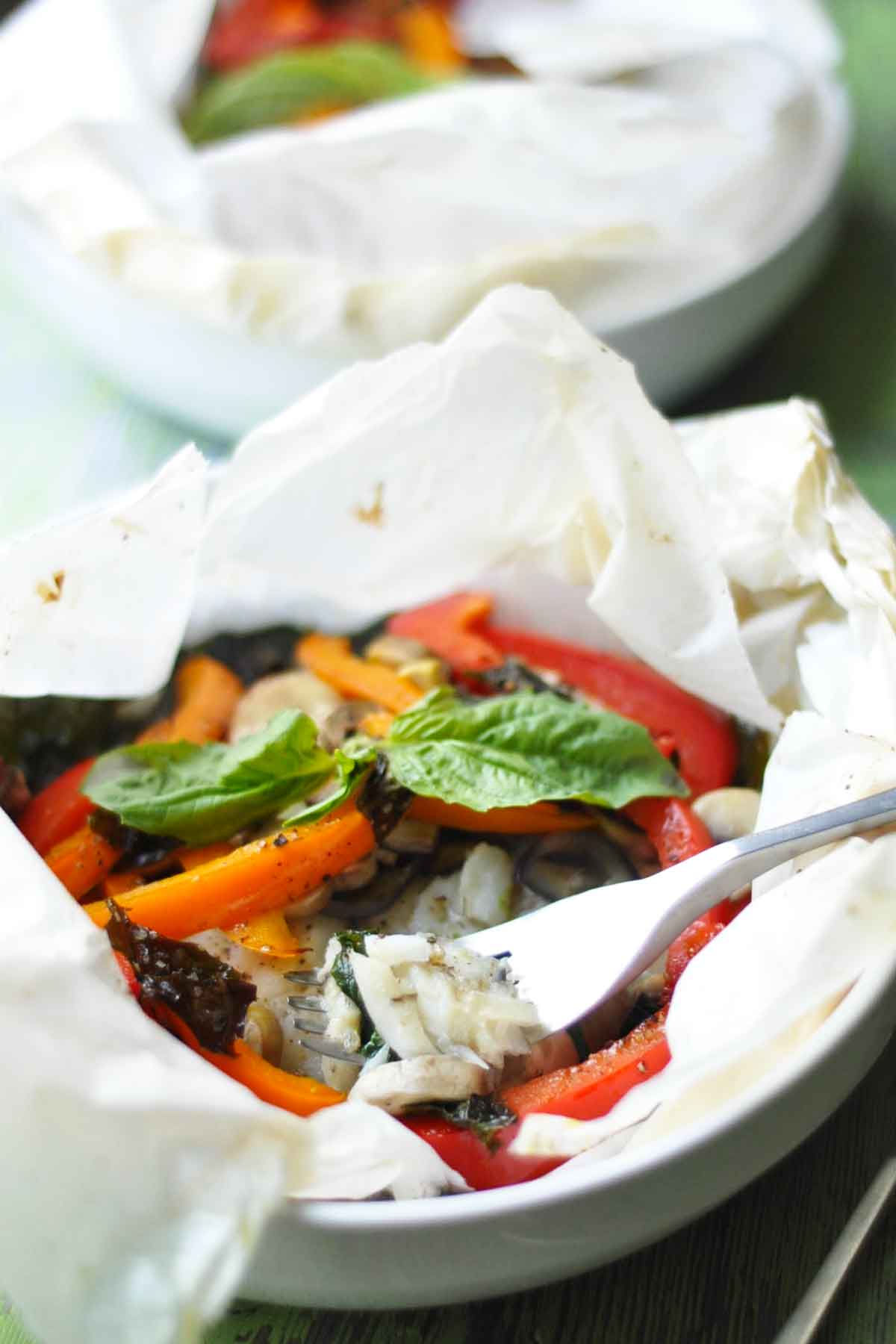 a close up of cod and vegetables cooked in a pocket en papillote