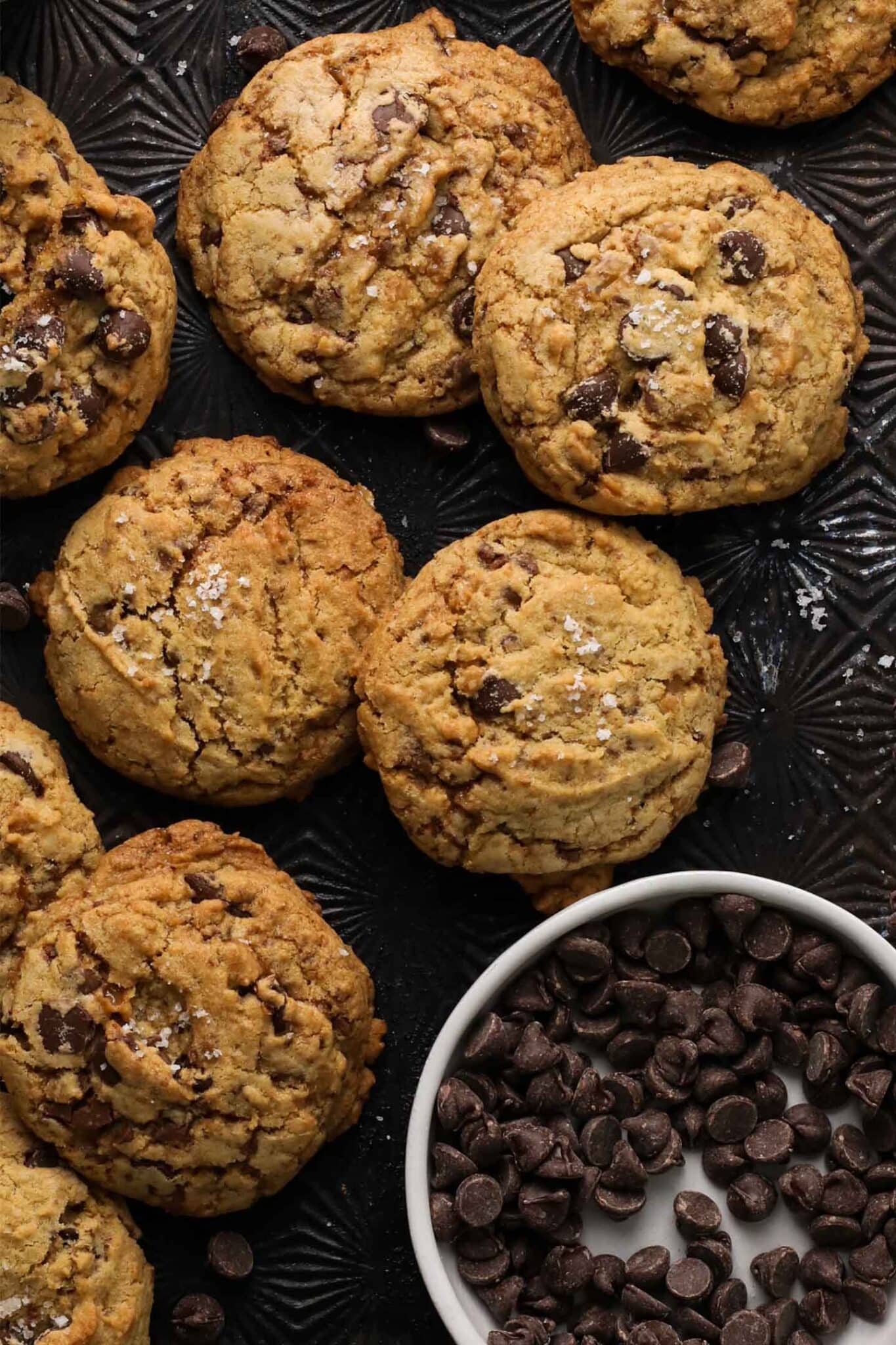 simple chocolate chip cookies with toffee bits and maldon salt on a black cookie tray