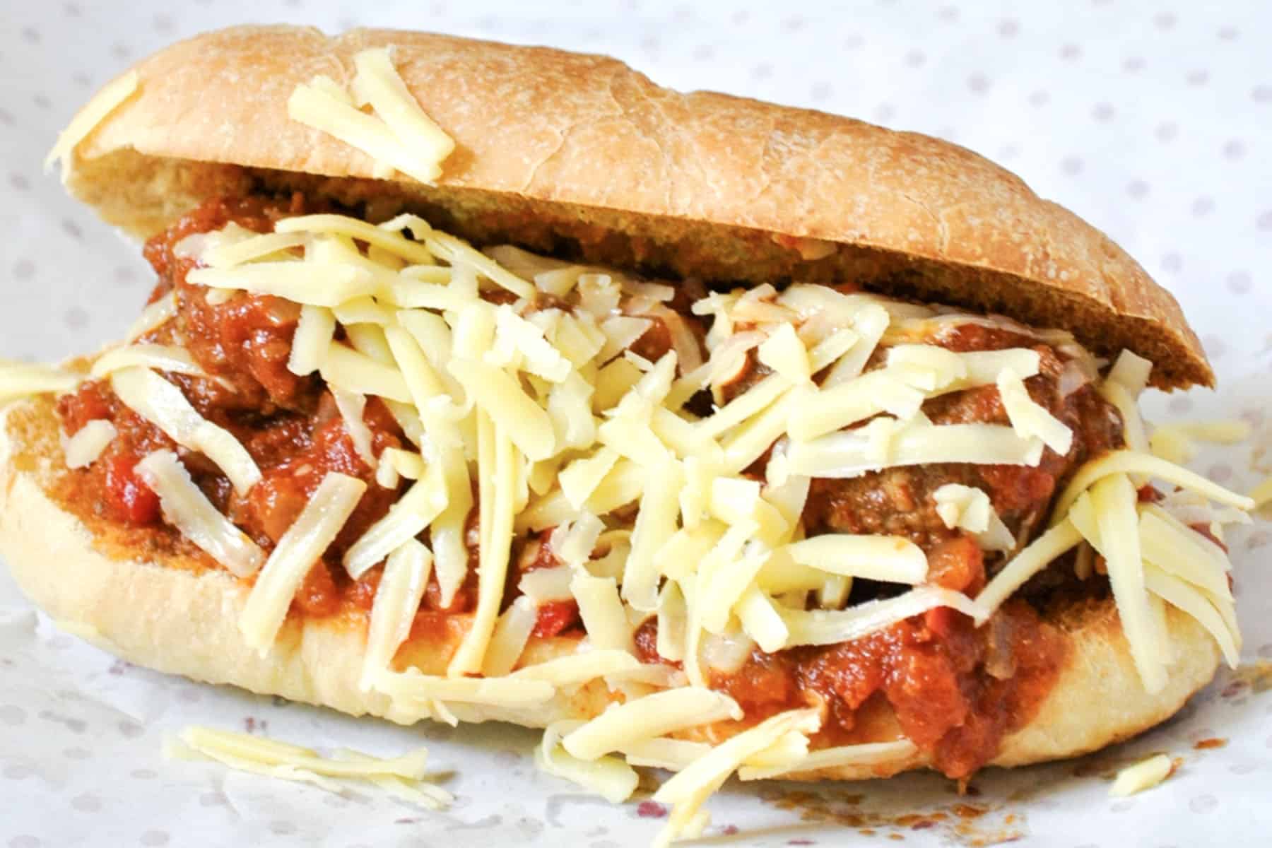 A classic meatball sub filled with juicy meatballs in tomato sauce, topped with shredded cheese and served on a crusty white roll.