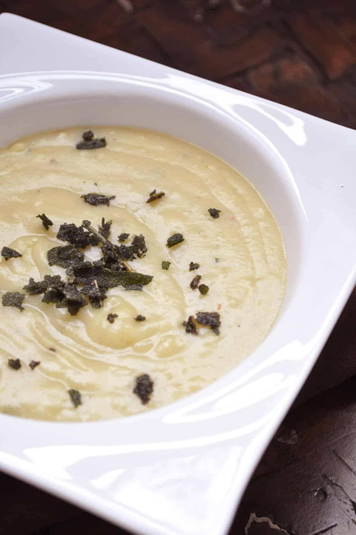 close up of creamy sweet potato soup with fried sage sprinkled on top