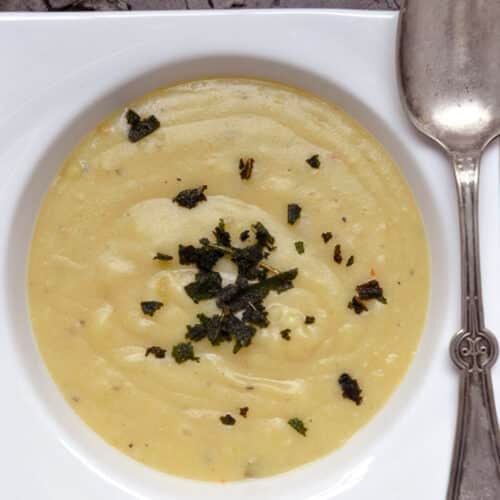a bowl of creamy sweet potato soup with fried sage topping