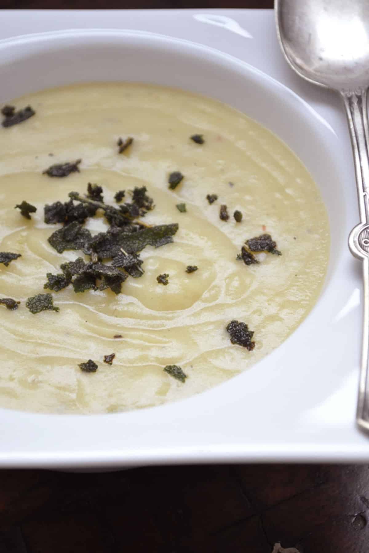 a bowl of creamy sweet potato soup with fried sage topping