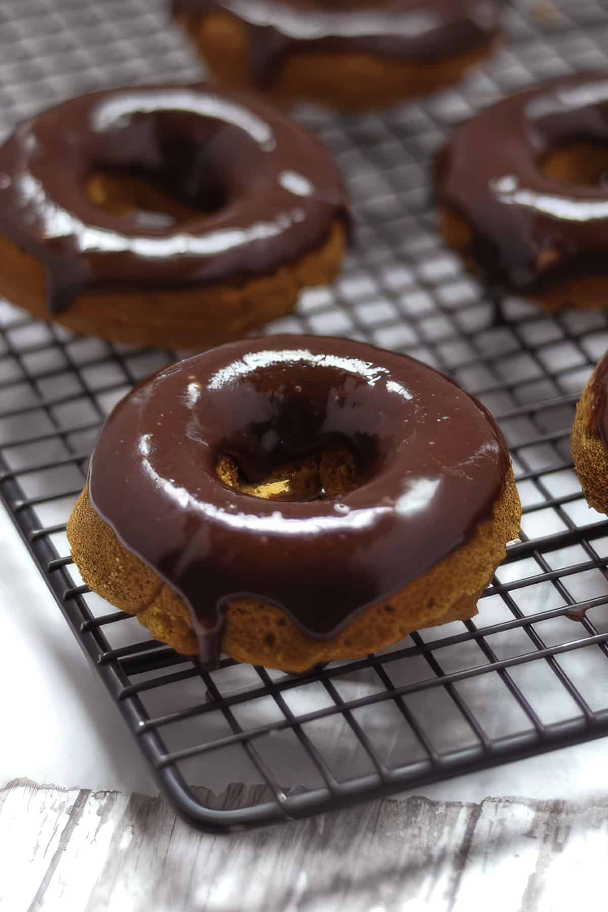 Gluten-free pumpkin donuts with chocolate glaze on cooling rack