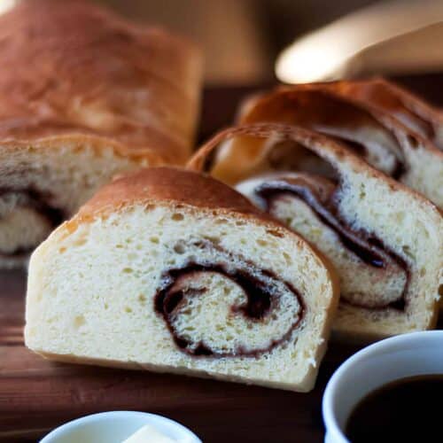 Freshly baked cinnamon swirl bread sliced on a wooden cutting board.