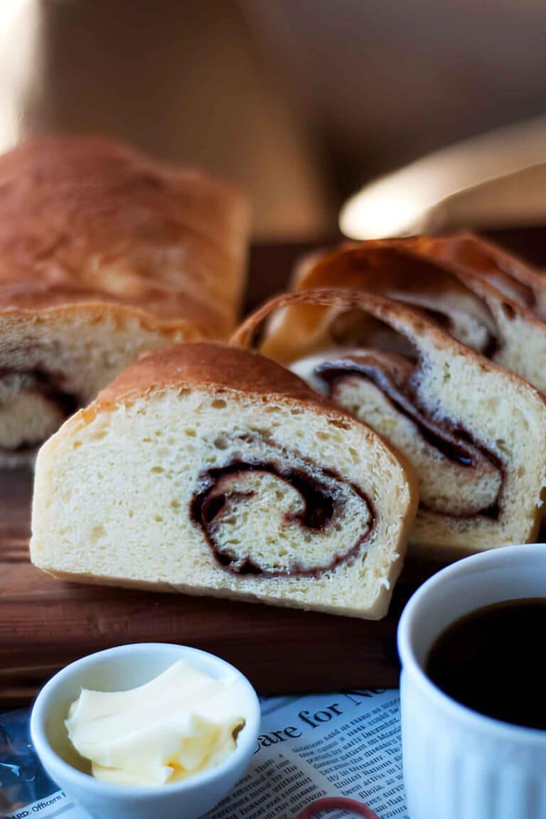 Freshly baked cinnamon swirl bread sliced on a wooden cutting board.
