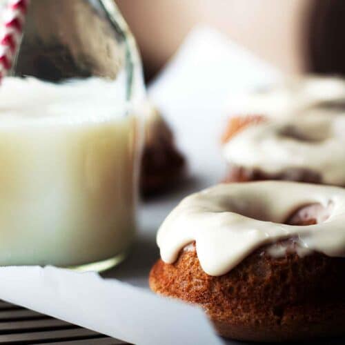 a close-up view of baked chai donuts with a bourbon glaze and a jug of milk