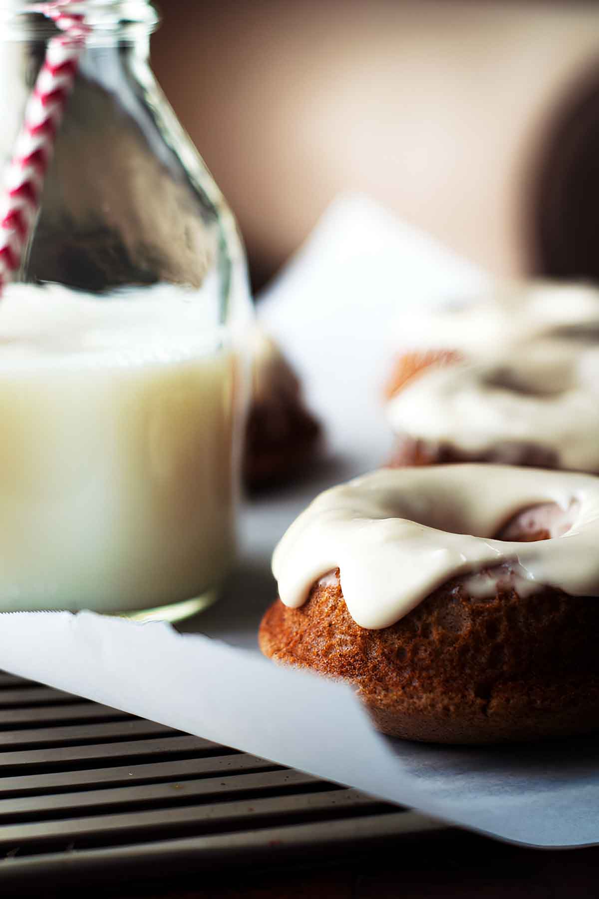 a close-up view of baked chai donuts with a bourbon glaze and a jug of milk