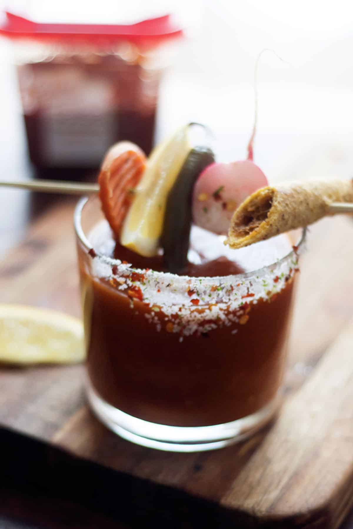 Close-up of spicy Bloody Maria with pickled jalapeños and lime wedge