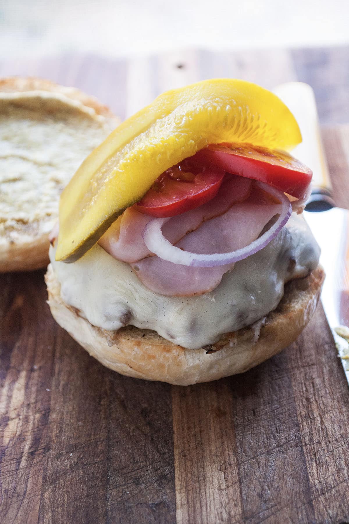 cuban burger on a bun with pickles, tomatoes and onions