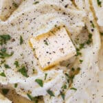 Creamy Yukon Gold mashed potatoes topped with a pat of butter, freshly ground black pepper, and chopped parsley.