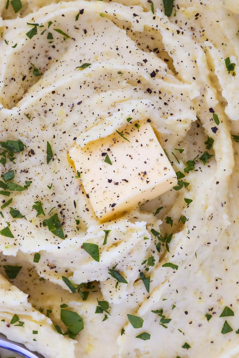 Creamy Yukon Gold mashed potatoes topped with a pat of butter, freshly ground black pepper, and chopped parsley.