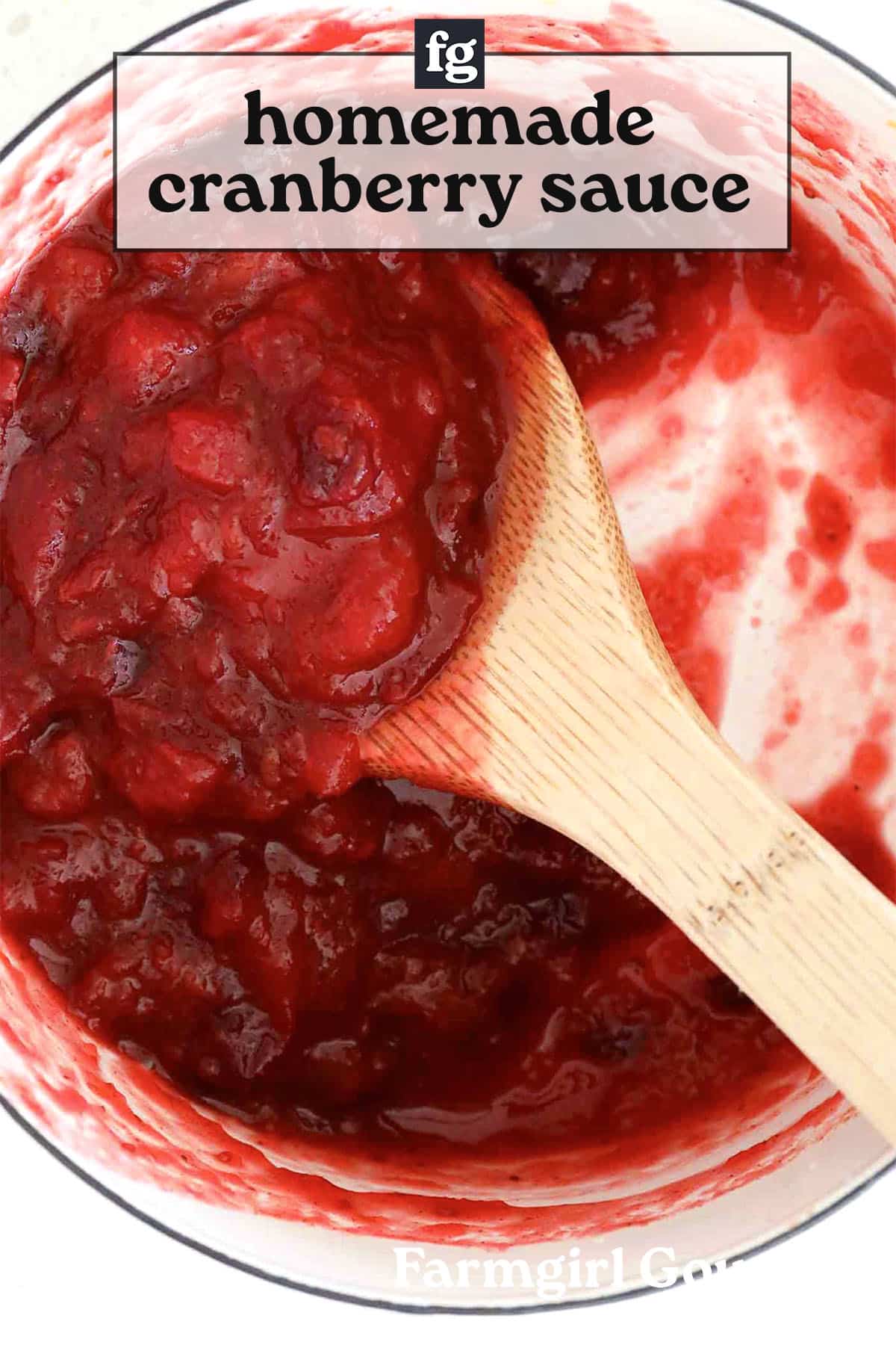 A wooden spoon stirs chunky homemade cranberry sauce in a white pot, with a label at the top reading "homemade cranberry sauce" and Farmgirl G visible at the bottom.