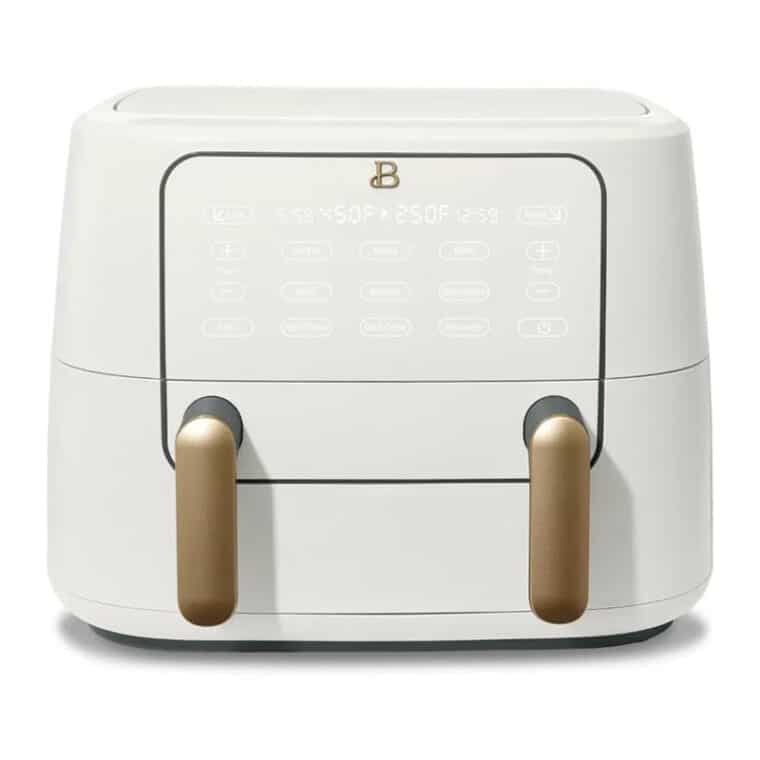 A white and gold dual-basket air fryer with a digital touch control panel on the front and two handles for pulling out the cooking baskets.