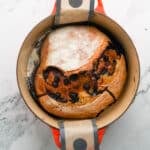 Freshly baked loaf in Dutch oven with golden crust