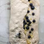 folding the bread dough with blueberry inclusions