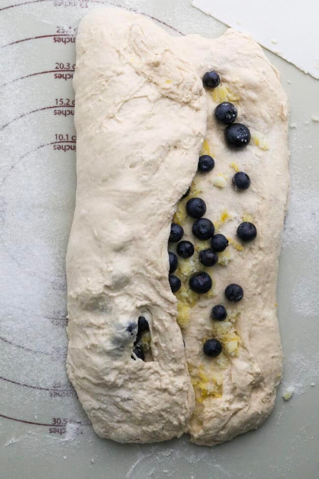 folding the bread dough with blueberry inclusions