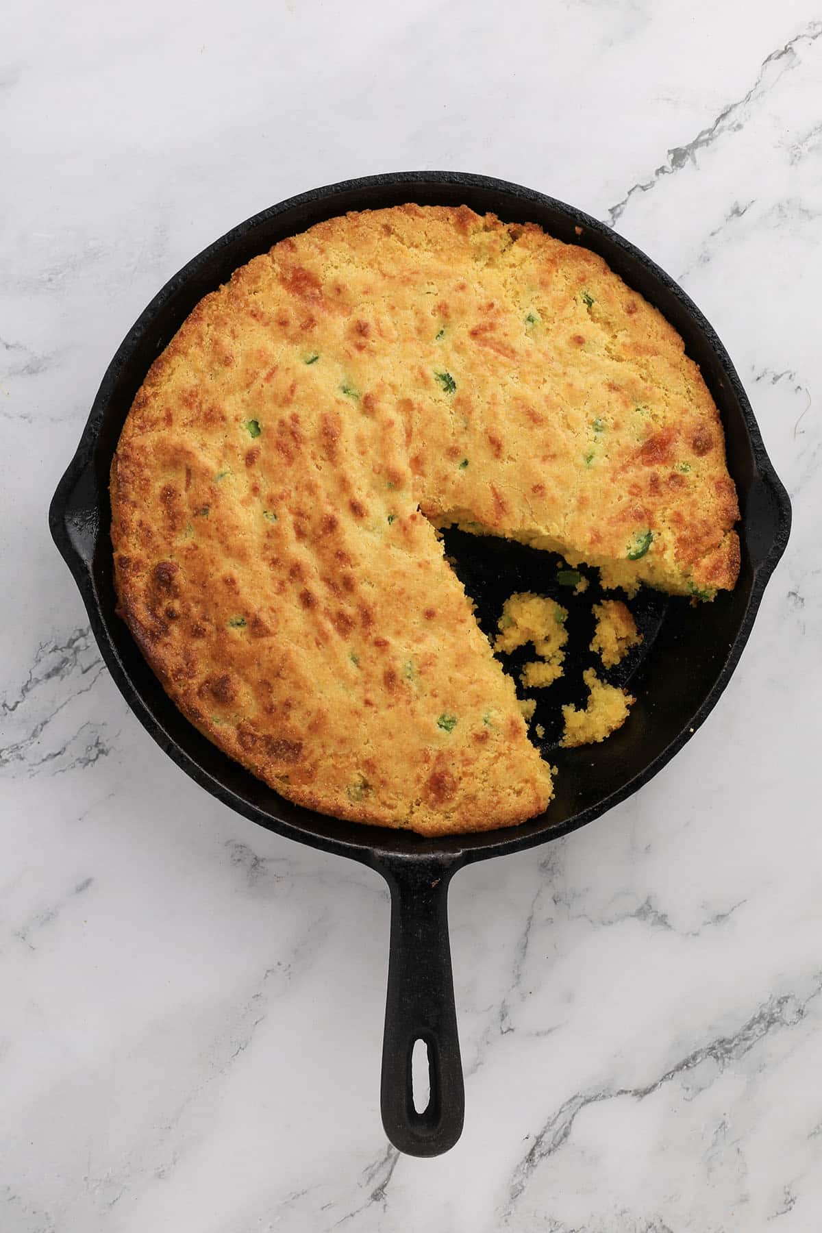 Overhead shot of golden jalapeño cheddar cornbread in a cast-iron skillet