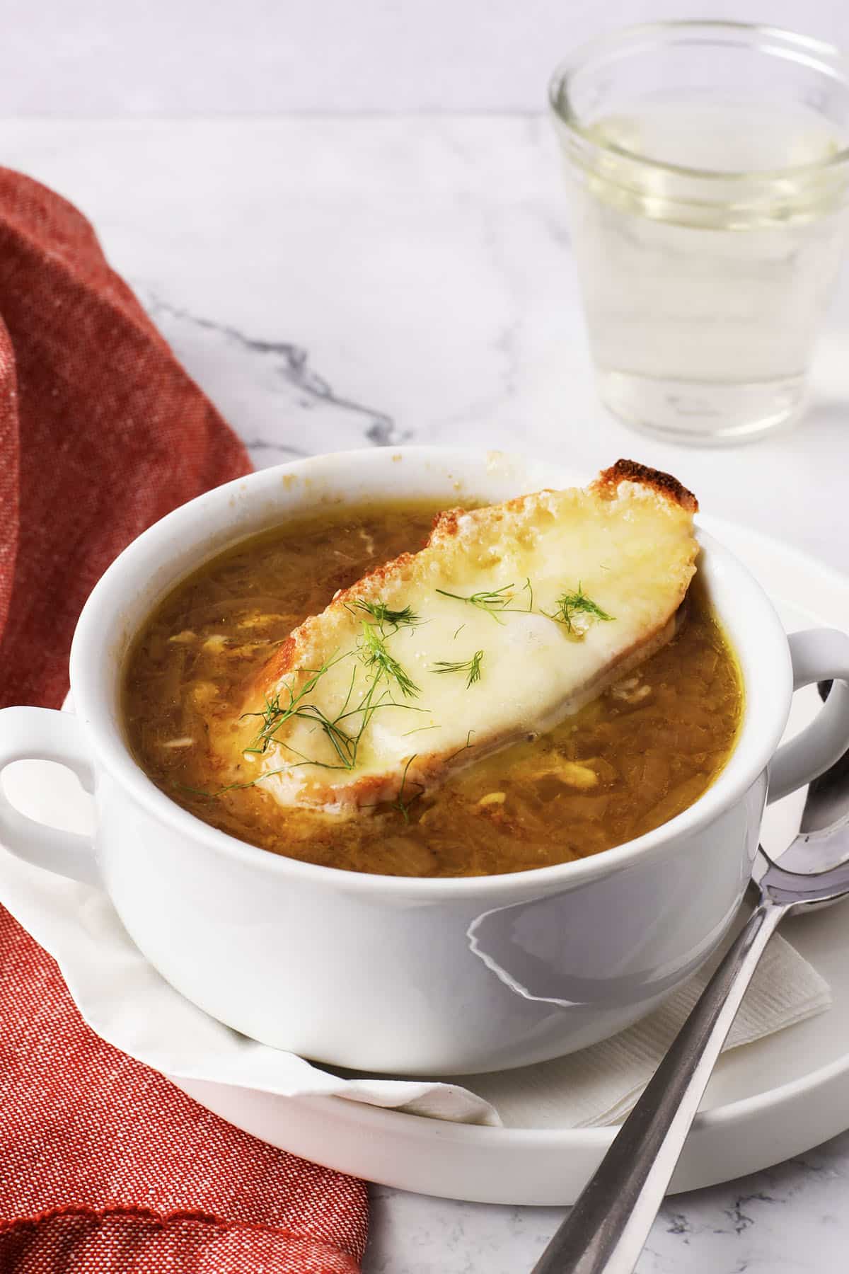 Toasted baguette slice covered in melted Gruyere on French onion soup