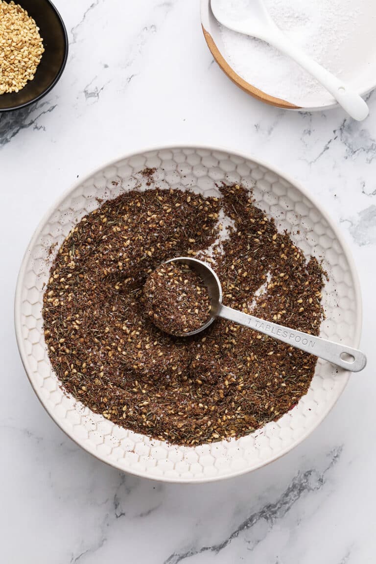 Spoon scooping Za’atar spice mix with sesame seeds visible