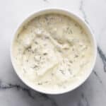Close-up of homemade tartar sauce with cornichons and herbs.