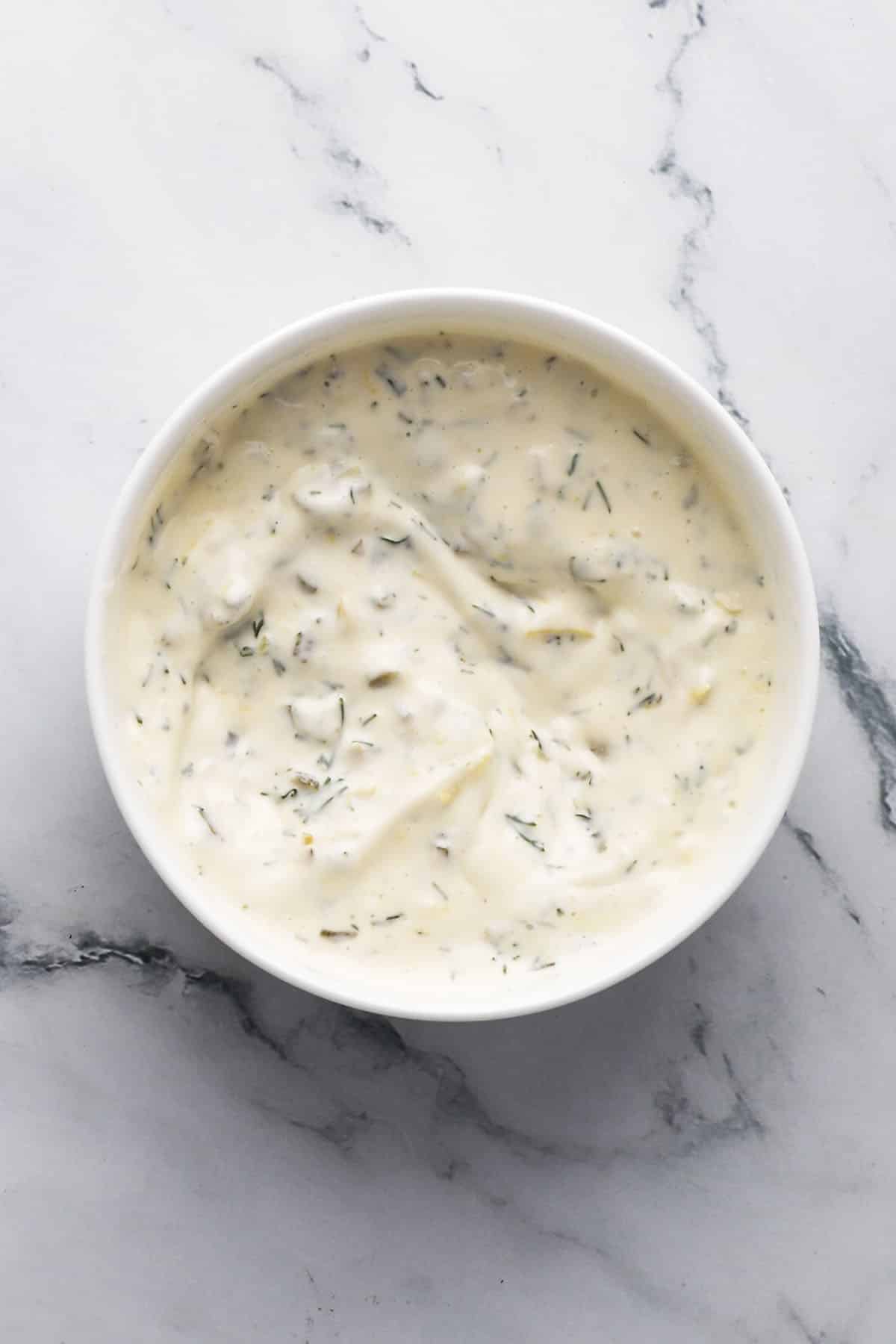 Close-up of homemade tartar sauce with cornichons and herbs.