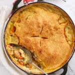 Golden turkey pot pie topped with flaky crust in a green baking dish
