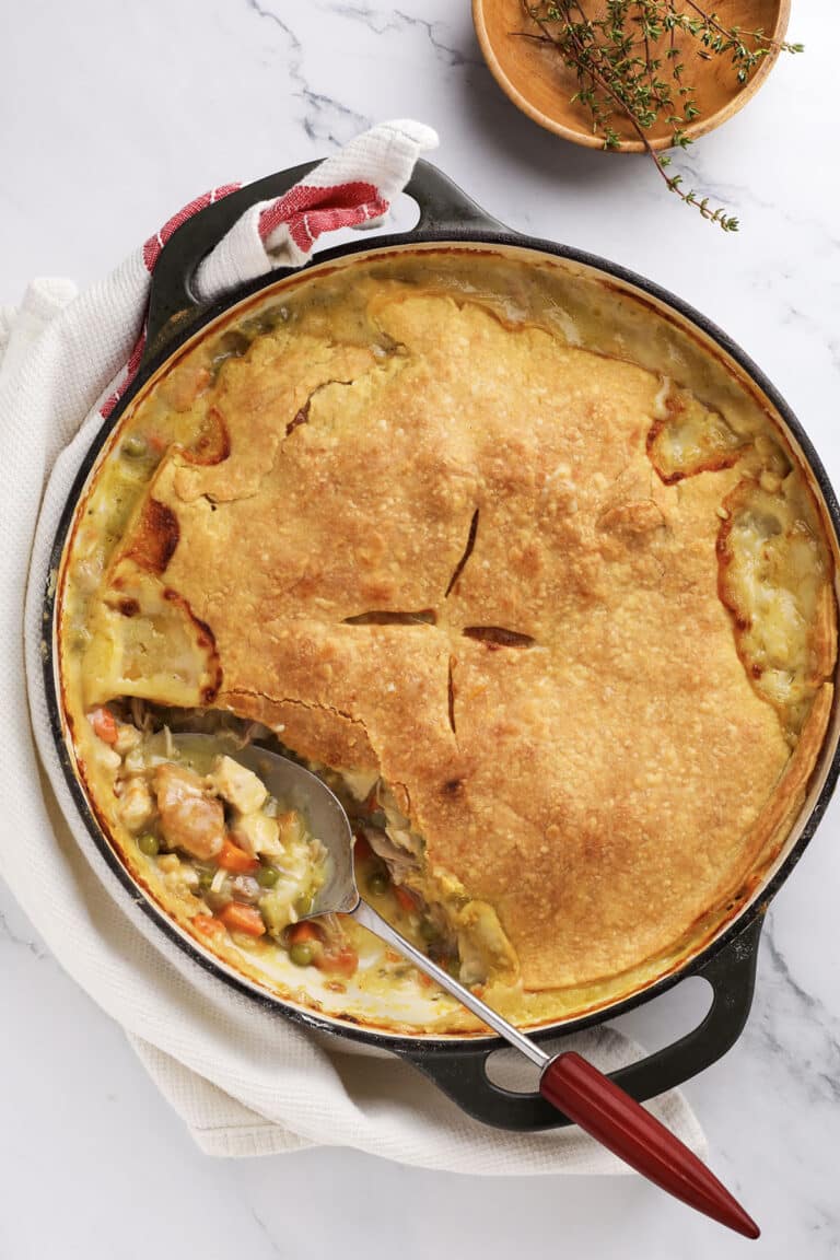 Golden turkey pot pie topped with flaky crust in a green baking dish