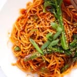 A bowl of noodles with broccoli and sesame seeds.