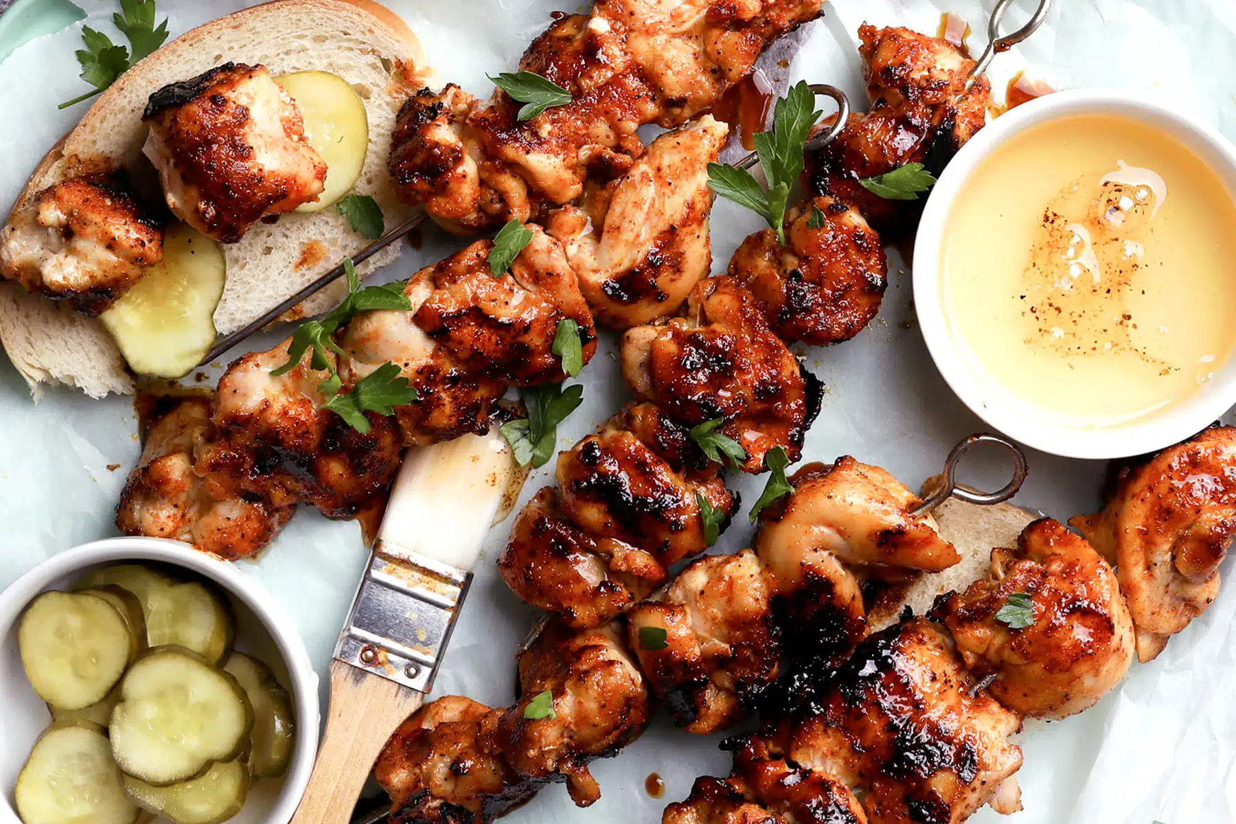 Nashville hot grilled chicken with dark cayenne crust grill marks and pickle slices on white bread on a plate