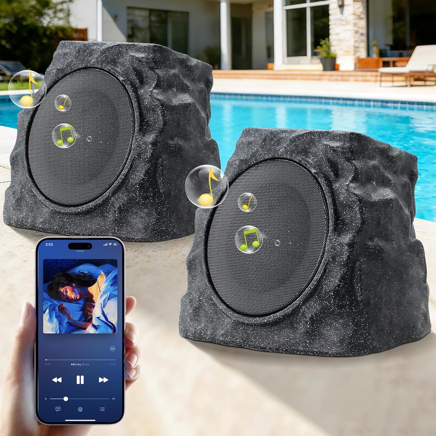 Two rock-shaped outdoor speakers are placed by a swimming pool, with a hand holding a phone in the foreground playing music. Yellow musical notes illustrate the sound coming from the speakers. A house is visible in the background.