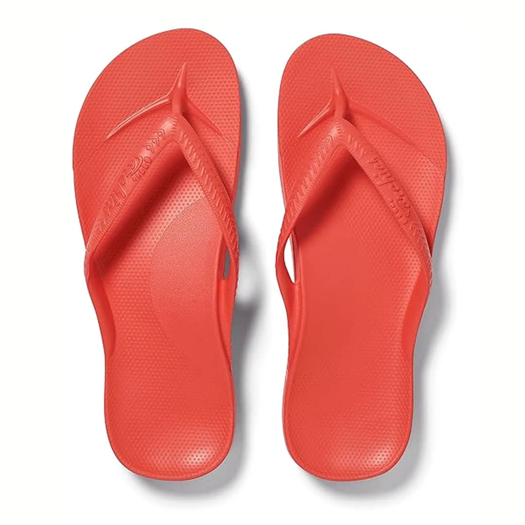 A pair of bright red flip-flops with textured footbeds and wide straps, viewed from above on a white background.