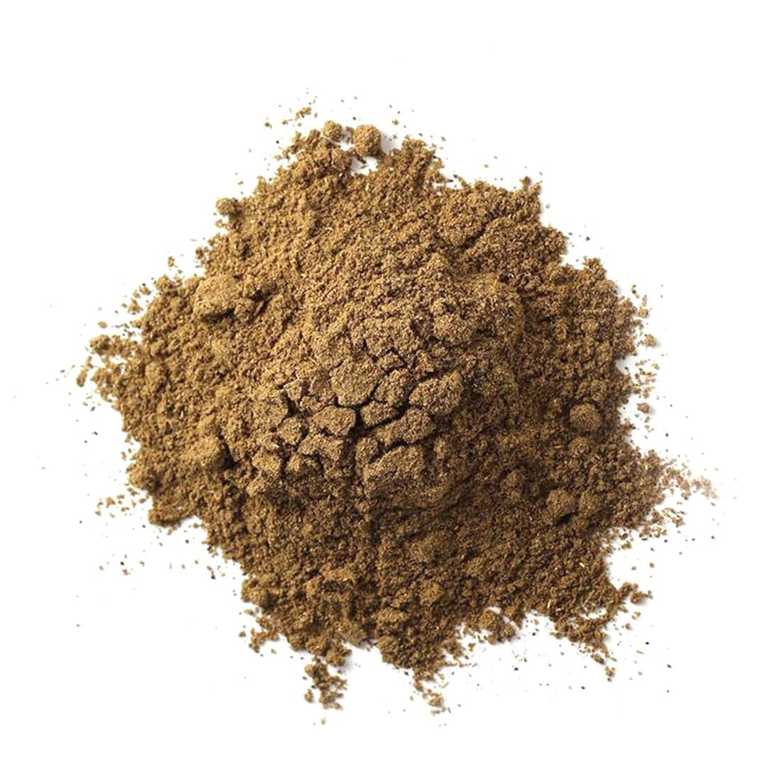 A pile of brown ground spice is scattered on a white background.