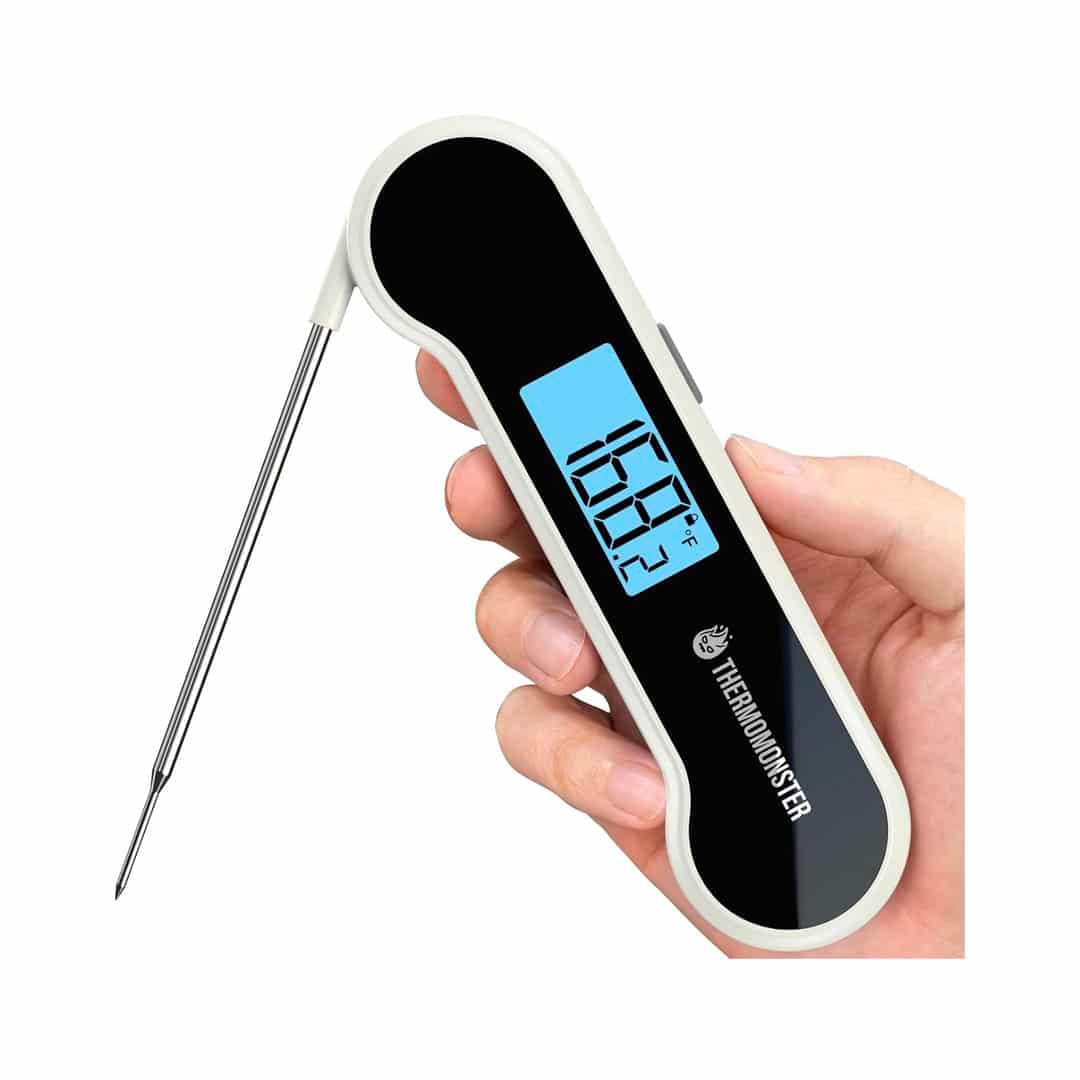 A hand holds a digital meat thermometer with a fold-out probe and a blue backlit display showing a temperature reading of 165.1°F—the perfect tool featured in our ultimate homemade bread guide for ensuring your loaves are baked to perfection.